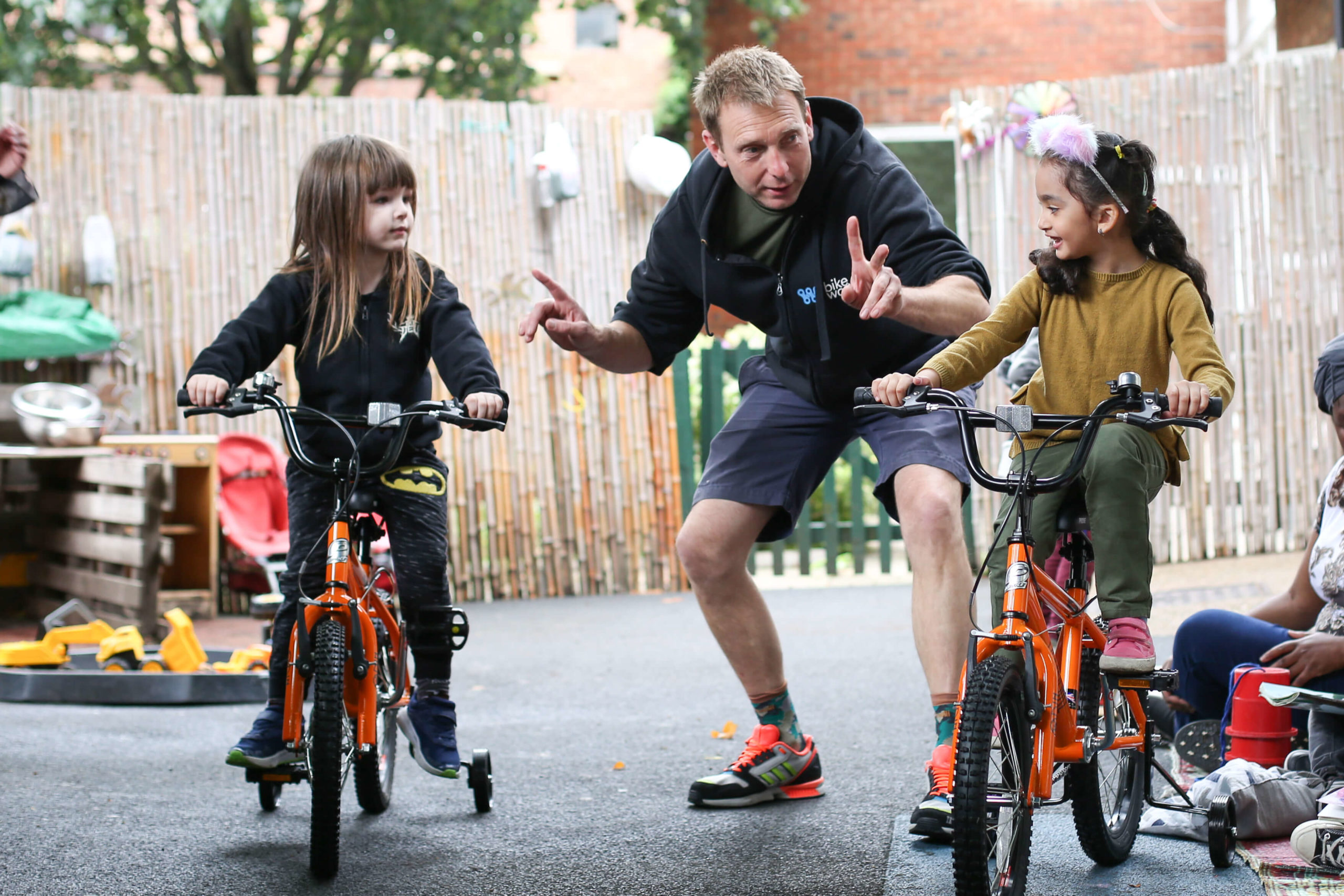 Jim at LEYF Nurseries with two early years students on cycles